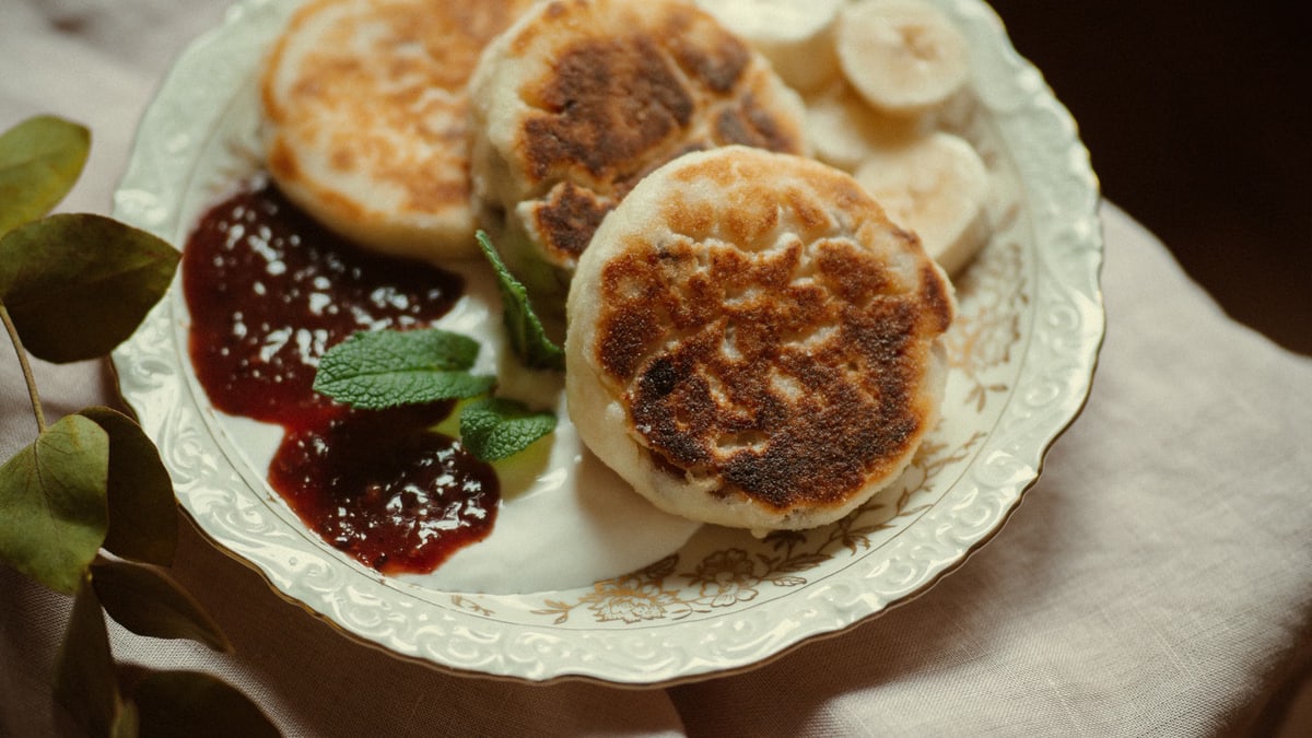 A lovely plate of homemade pancakes with banana slices and raspberry jam, perfect for breakfast.
